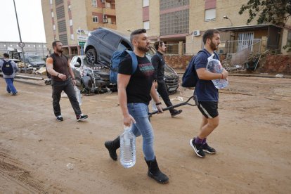 Varios residentes llevan garrafas de agua a la entrada de la localidad de Paiporta, Valencia, este jueves.