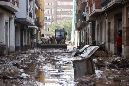 Una máquina excavadora retira el lodo acumulado en las calles tras las intensas lluvias caídas por la fuerte dana, este jueves en Catarroja.