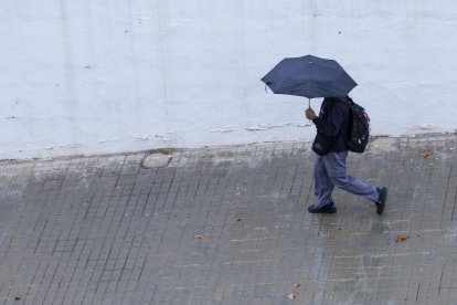 Un joven se protege de la lluvia con un paraguas en Valencia, en una imagen de archivo. EFE/Kai Försterling