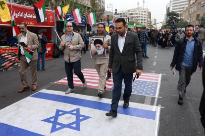 Iraníes caminan sobre banderas de Estados Unidos e Israel durante una manifestación antiestadounidense con motivo del 45 aniversario de la toma de la embajada de Estados Unidos, frente al antiguo edificio de la legación diplomática en Teherán, el 3 de noviembre de 2024. EFE/EPA/ABEDIN TAHERKENAREH