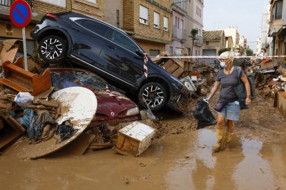 Los vecinos limpian las calles junto a varios coches apilados en Catarroja, Valencia este martes, una de las localidades más afectados por las inundaciones. EFE/ Chema Moya