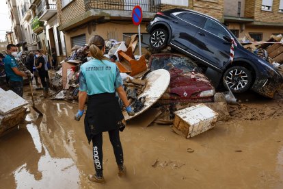 Los vecinos limpian las calles junto a varios coches apilados en Catarroja, Valencia este martes, una de las localidades más afectados por las inundaciones. EFE/ Chema Moya