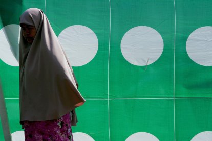 Fotografía de archivo de una mujer andando frente a un cartel electoral en Kuala Terengganu, la capital de la provincia de Terengganu, en el norte de Malasia. EFE/Shamshahrin Shamsudin