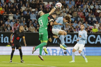 El guardameta del Celta, Vicente Guaita (i), despeja el balón ante su compañero, Marcos Alonso y el delantero polaco del FC Barcelona, Robert Lewandowski, durante el encuentro correspondiente a la jornada 14 de Laliga EA Sports que disputan hoy sábado Celta y FC Barcelona en el estadio Balaidos de Vigo. EFE / Emilio Lavandeira.