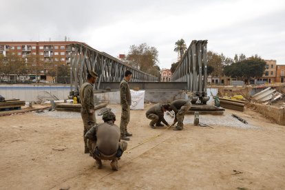 Zapadores del ejército de Tierra avanzan en la construcción de una pasarela militar en Picanya (Valencia), este domingo. Tras haberse retirado más de 150.000 toneladas de residuos y enseres de los municipios de Valencia afectados por la dana de hace veintiséis días, en este cuarto domingo desde las inundaciones siguen las labores de limpieza, con un refuerzo del operativo para extraer el lodo de sótanos, bajo y garajes y evitar problemas de salud pública. EFE/Villar López