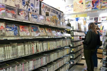 Unas personas frente a una estantería con juegos usados de PlayStation a la venta en una tienda de videojuegos retro en Tokio, el 3 de diciembre de 2024. EFE/EPA/CHRISTOPHER JUE