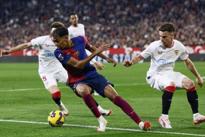 El delantero del FC Barcelona Lamine Yamal (2i)se escapa de la presión de varios jugadores sevillistas durante un encuentro correspondiente a la jornada 23 de LaLiga EA Sports entre el Sevilla FC y el FC Barcelona en el estadioo Ramón Sánchez-Pizjuán de Sevilla. EFE/ Julio Munoz
