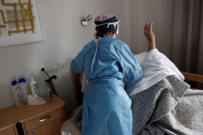Una trabajadora atiende a un anciano en una residencia durante la pandemia.