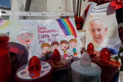 Un dibujo y una fotografía del papa Francisco bajo la estatua de Juan Pablo II, frente al Hospital Agostino Gemelli, donde se encuentra hospitalizado desde el 14 de febrero debido a una infección en las vías respiratorias. EFE/EPA/GIUSEPPE LAMI