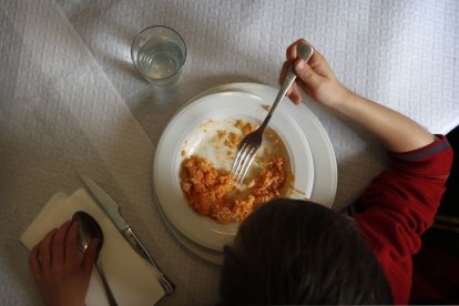 Un menor come arroz en un restaurante.