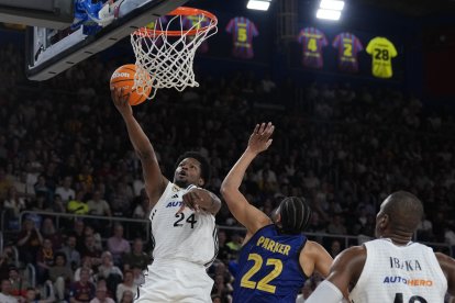 El base dominicano del Real Madrid Andrés Feliz (i) entra a canasta ante el alero estadounidense del FC Barcelona Jabari Parker (c) durante el encuentro correspondiente a la fase regular de la Liga Endesa que disputaron en el Palau Blaugrana de Barcelona. EFE / Alejandro García.