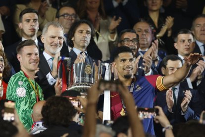 Los jugadores del FC Barcelona, el uruguayo Ronald Araujo (d) y el alemán Marc-André ter Stegen, reciben el trofeo de campeones de manos del rey Felipe.