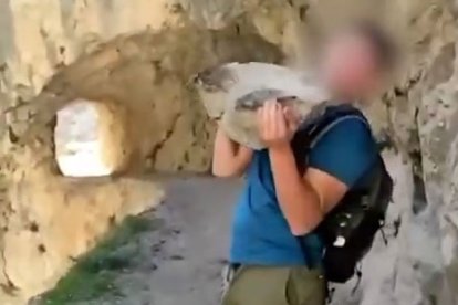 Captura del vídeo en el que se ve al joven lanzando una piedra de gran tamaño en uno de los desfiladeros de la Ruta del Cares