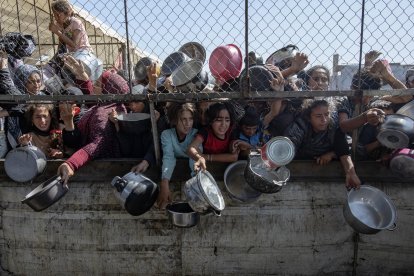 Palestinos desplazados se agolpan frente a un comedor social para recibir raciones de alimentos al sur de la Franja de Gaza. EFE/ Haitham Imad.