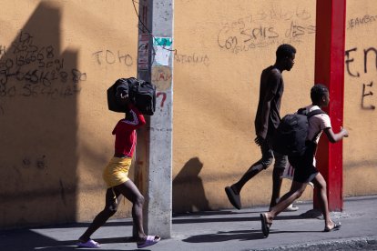 Fotografía de archivo del 23 de febrero de 2025 de tres personas caminando con sus pertenencias en Puerto Príncipe (Haiti). EFE/ Mentor David Lorens.