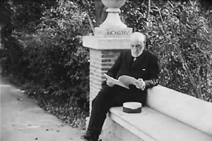 Santiago Ramón y Cajal sentado en un banco mientras lee.