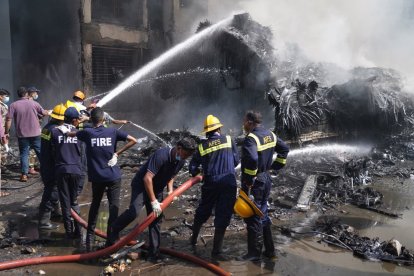Bombreos apagan el fuego del avión que cayó sobre una residencia de estudiantes.
