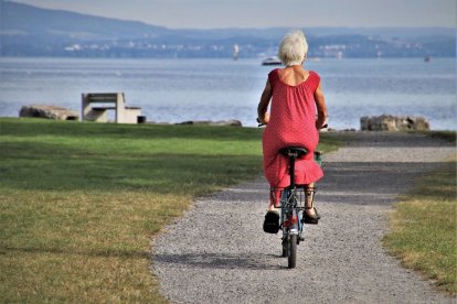 Una mujer mayor pasea en bicicleta cerca de la playa.