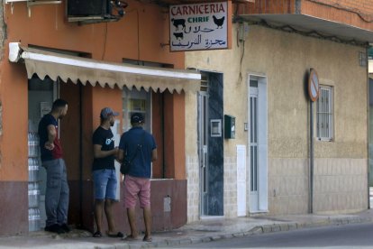 Un grupo de vecinos a la puerta de un establecimiento de Torre Pacheco.