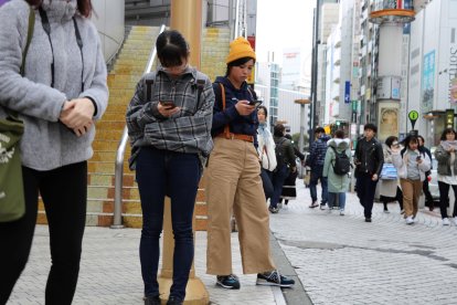 Jóvenes utilizan el móvil en las calles del barrio de Shibuya, en Tokio.