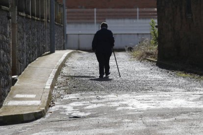 Una persona mayor camina sola por las calles de un pueblo de León.