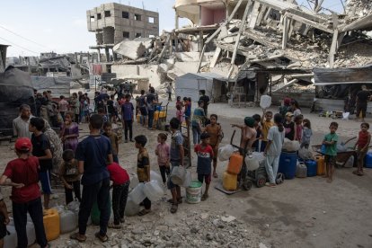 Un grupo de niños hace cola para coger agua potable en Gaza.