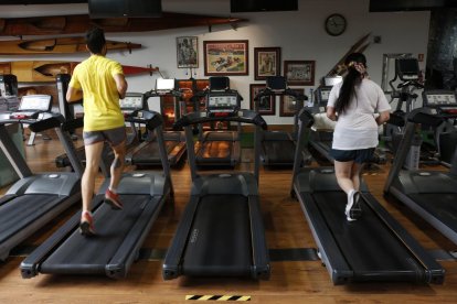 Dos personas hacen ejercicio en un gimnasio.