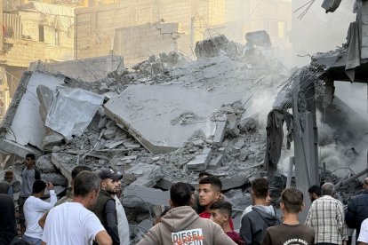 Un grupo de palestinos observa los escombros tras uno de los ataques lanzados por Israel ayer en Gaza.