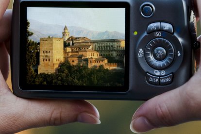 Un hombre toma fotografias de la Alhambra de Granada en sus vacaciones.