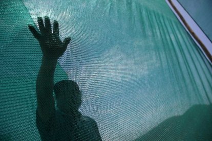 Una persona tocando la malla de un sistema de captación hídrica en Lima (Perú).