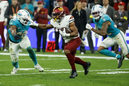 Un jugador de los Washington Commanders con el balón ante varios rivales de los Miami Dolphins, durante el partido de liga regular de la Liga de Fútbol Americano (NFL), que este domingo disputan en el Santiago Bernabéu.