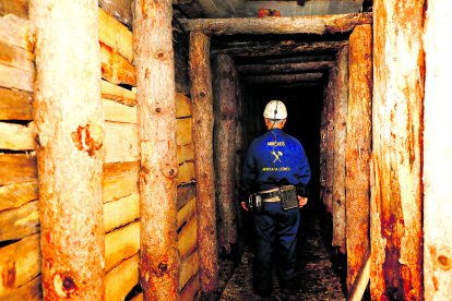 Un minero camina por la galería de madera en la mina escuela museo de La Robla.