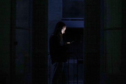 Un joven consulta su teléfono móvil en un balcón de Barcelona durante el apagón. EFE/Alberto Estévez.