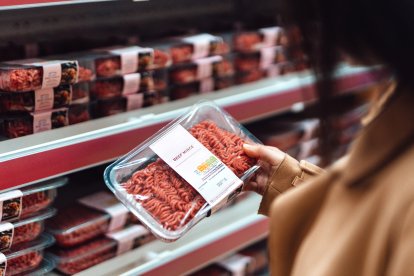 Una mujer observa el etiquetado de carne envasada en un supermercado