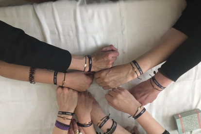 Un grupo de mujeres de la Semana Santa de León juntas sus manos en una señal de apoyo mútuo y fuerza.