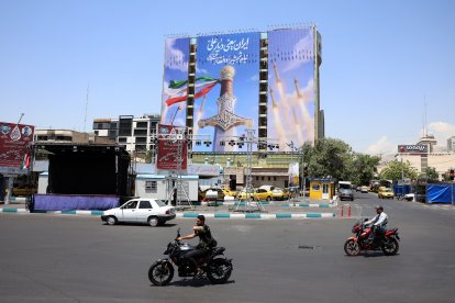 Ciudadanos iraníes pasan ante una gran valla publicitaria con misiles de Irán instalada en Teherán.