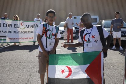 Dos niños saharauis muestran la bandera de su país en el exilio, con la pancarta de la asociación Asped detrás.