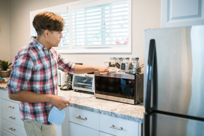Hombre pone en orden y deja los electrodomésticos de la cocina antes de las vacaciones.