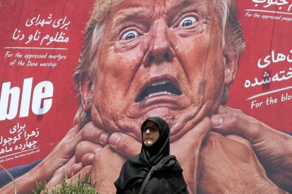 Una mujer pasa junto a una valla anti-Trump.