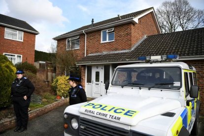 Agentes de policía británicos permanecen en guardia a la entrada de una vivienda.