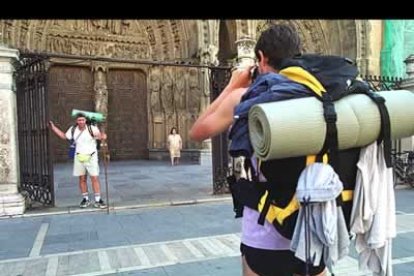 Una pareja de peregrinos se hace fotos frente a la catedral leonesa.