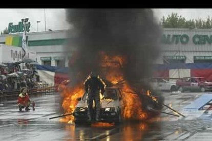 Un especialista, sentado sobre un coche, cruza a toda velocidad sobre un muro de fuego.