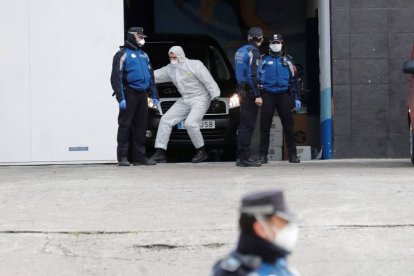 Miembros de la policía junto a uno de los trabajadores de la morgue que ha sido instalada en el Palacio de Hielo. CHEMA MOYA