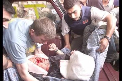 Los reporteros portan a uno de sus compañeros heridos en el ataque.