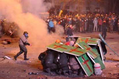 Unos manifestantes se protegen de la policía antidisturbios, desafiando los nuevos y estrictos límites a las protestas. AFP PHOTO / GENYA SAVILOV