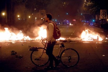 Un hombre camina junto a una barricada de fuego en la Gran Vía. TONI ALBIR