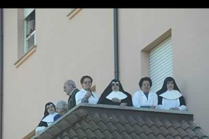 Un grupo de hermanas sigue la procesión del perdón desde un balcón.