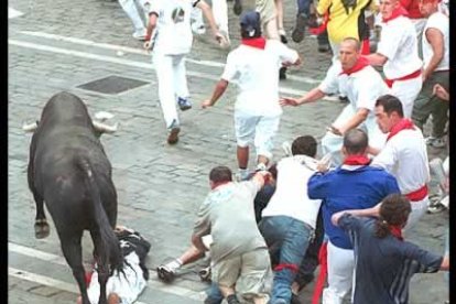 Un tramo del encierro a su paso por el Ayuntamiento, donde varios mozos permanecen tumbados ante el paso de la manada.
