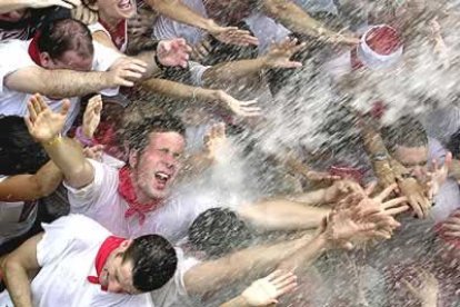 Varios jóvenes pamplonicas, ataviados con la tradicional pañoleta, reciben una lluvia de caba durante el chupinazo que marca el inicio de los sanfermines.