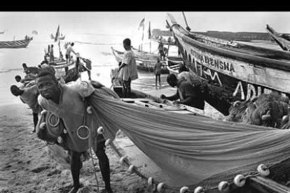 La fotografía en blanco y negro muestra a un pescador de Ghana limpiado sus redes tras una dura jornada de pesca.